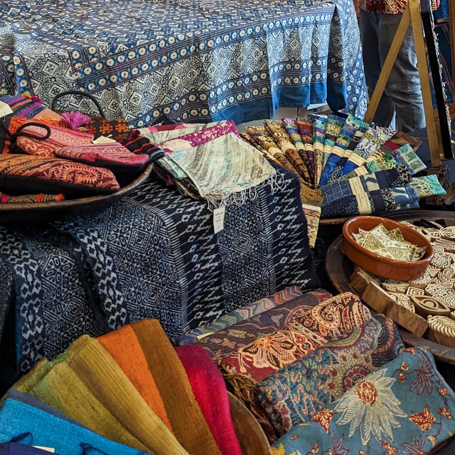 Asian textiles and handwoven silk scarves displayed on a textile market stall in the UK