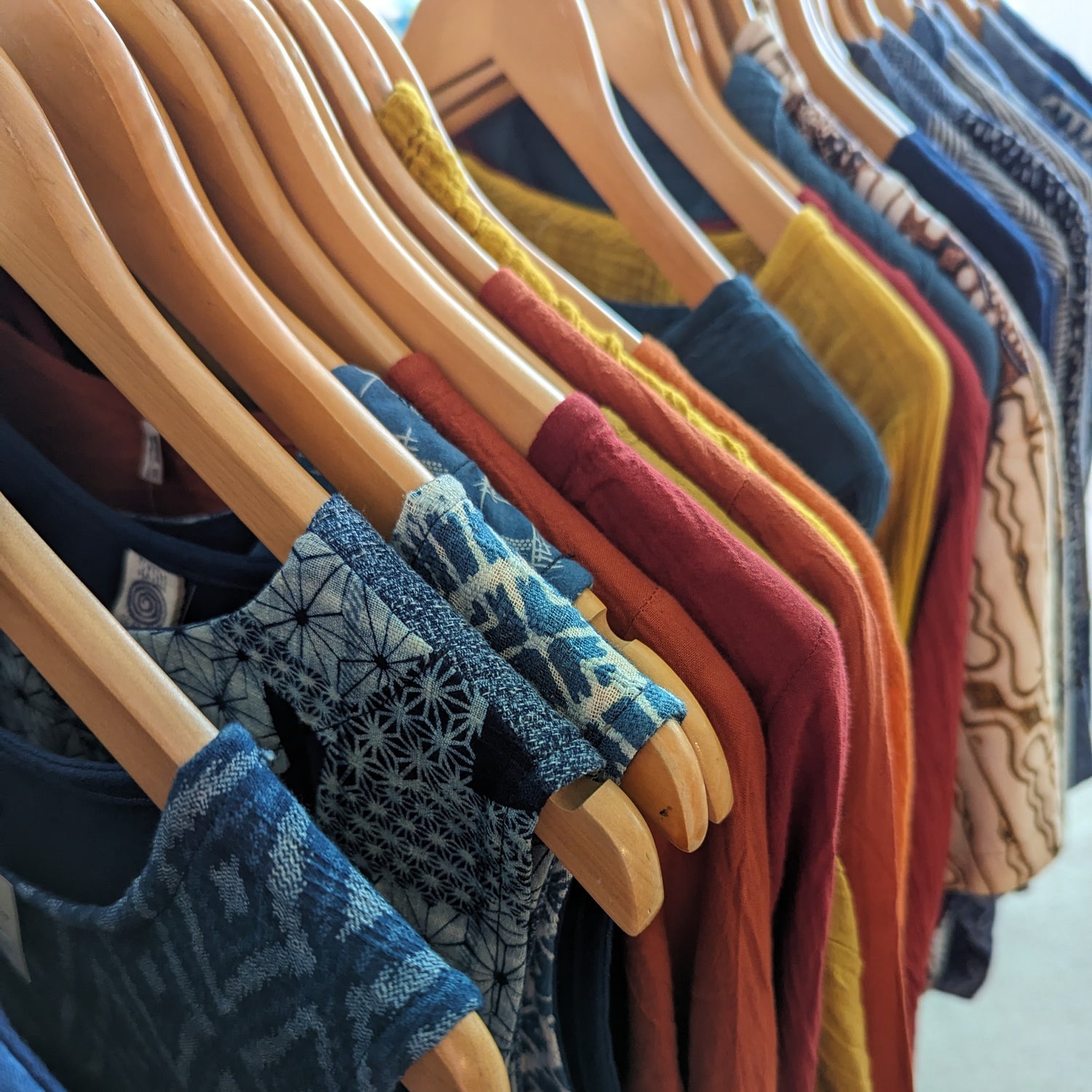 Batik shirts, cheesecloth tops and indigo clothing hanging on a rail at a UK textile market.